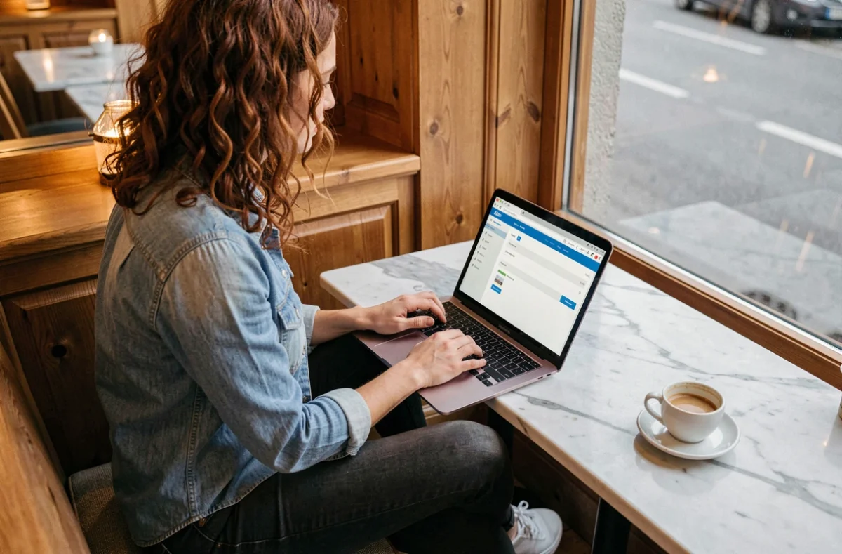 Jeune femme utilisant Swiss Transfer pour envoyer des fichiers volumineux depuis un café suisse avec son ordinateur portable